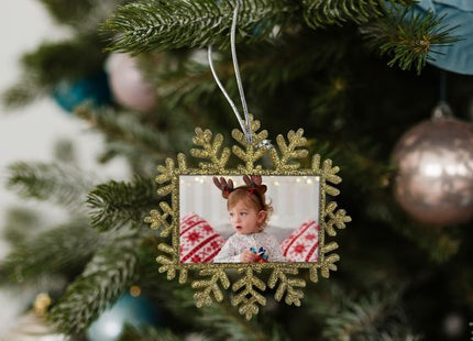 Gold glitter Christmas snowflake photo ornament hanging on a Christmas tree